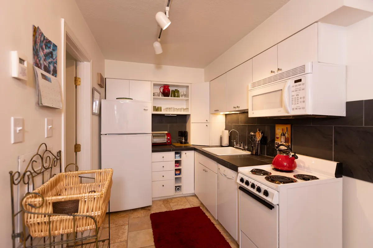 A cozy and practical kitchen scene featuring modern appliances, expansive counter space, and a distinctive red kettle, inviting guests to prepare meals or gather for conversation.