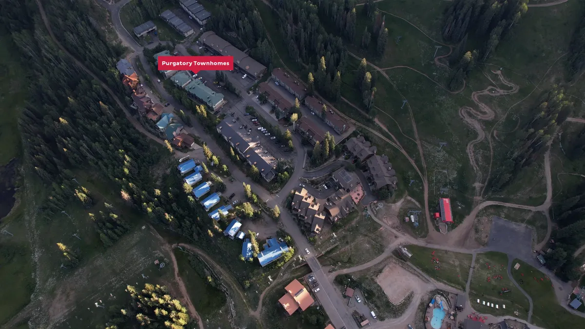 This exterior image features the Purgatory Townhomes nestled amidst lush natural surroundings, with the mountainous San Juan landscapes in the background. The architecture is welcoming, and there are clear visuals of the community's proximity to nature trails and open spaces, inviting exploration and adventure.